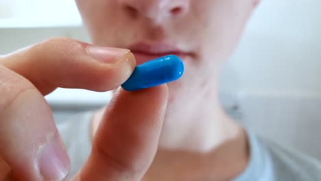 close-up of a young teenage male nervously contemplating taking a pill