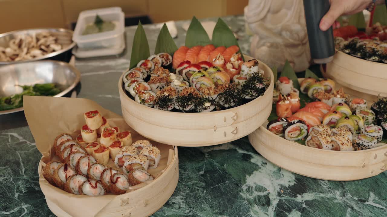 assorted sushi rolls with sauces and garnish displayed on bamboo trays