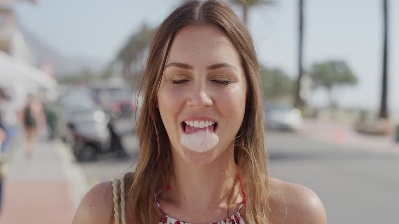 retrato de una hermosa mujer joven soplando burbuja de chicle riendo feliz disfrutando de unas vacaciones de verano relajadas en una soleada playa urbana