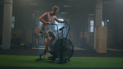 fitness man on bicycle doing spinning at gym. fit young male working out on gym bike. male exercising on bicycle in health club