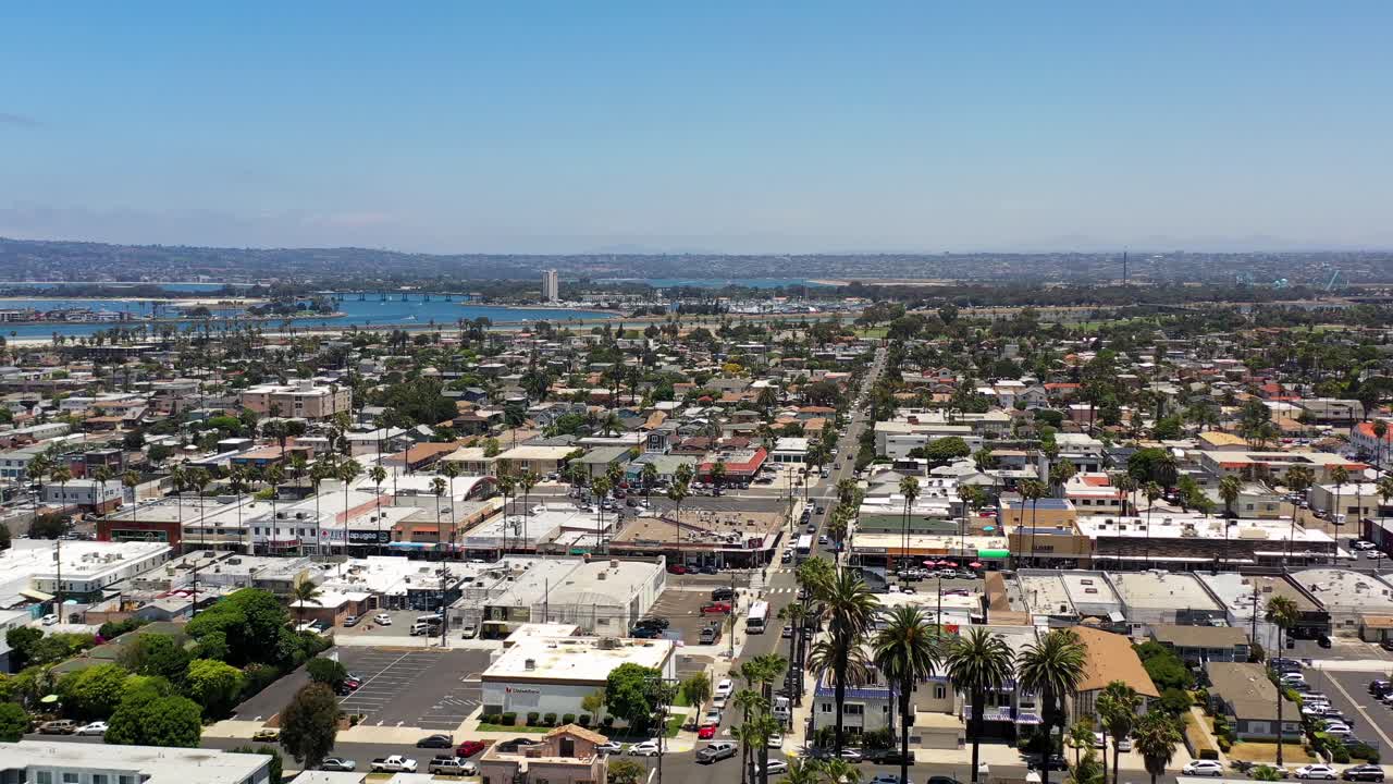 Dron letí nad domy v Ocean Beach San Diego, směřuje k Newport Avenue a snímá uspořádání čtvrti a pobřeží.