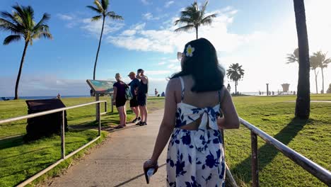 backside view of tourist girl in dress at sandy poipu beach on a sunny day on the island of kauia, hawaii, popular snorkeling spot on south shore, named best beach in america. tourists at poipu