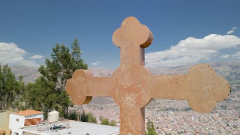 aerial drone orbits the large stone cross at rataquenua viewpoint, revealing panoramic views of huaraz cityscape and majestic andes mountains in peru