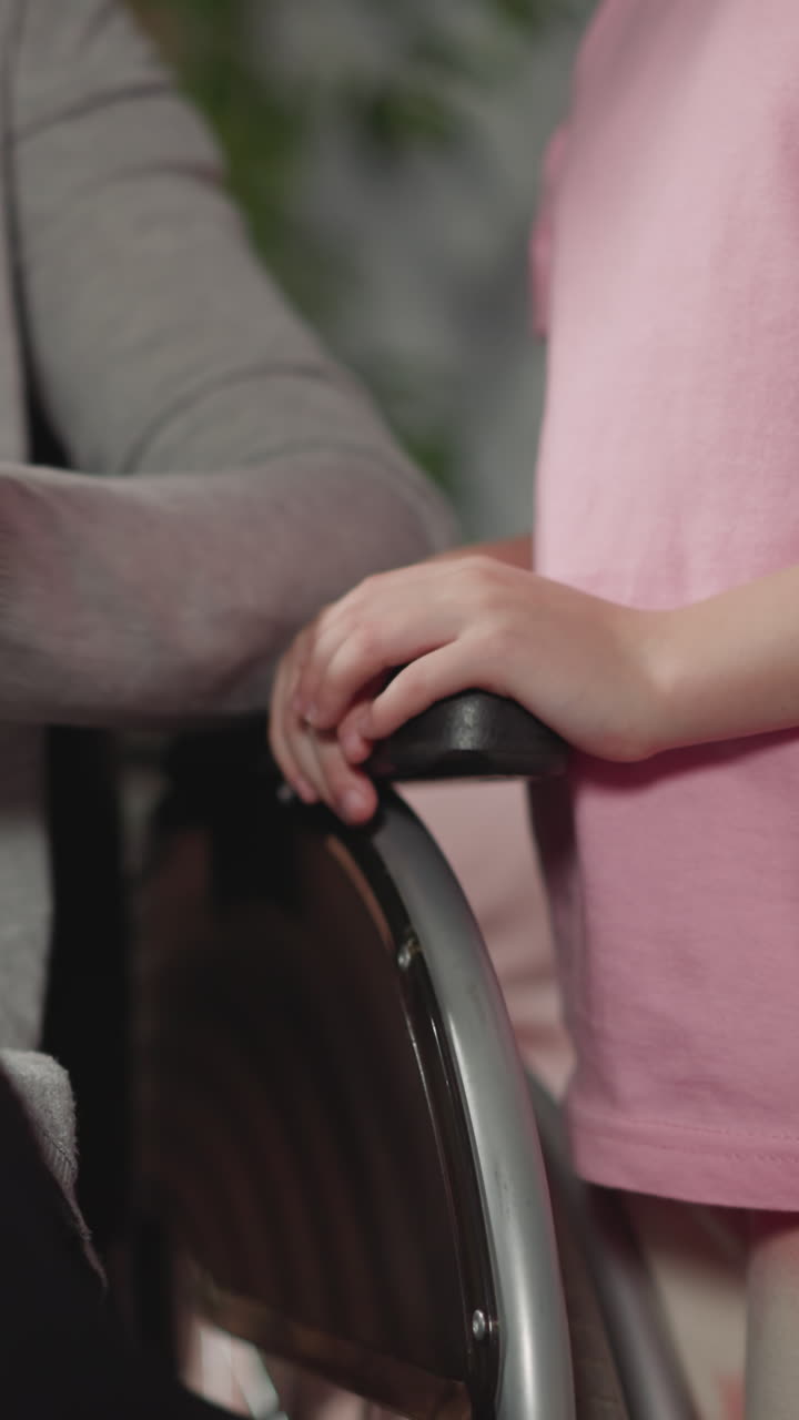 niña pequeña mira a su madre desplazarse por las redes sociales en la tableta. mujer con discapacidad se sienta en silla de ruedas eligiendo un juego para jugar con su hija de cerca