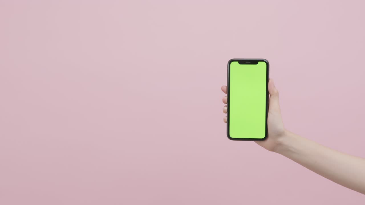 mano sosteniendo un teléfono inteligente con pantalla de tecla de croma y mostrando en el fondo rosa.