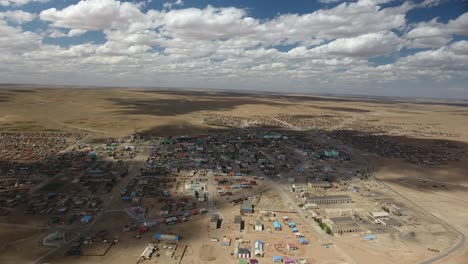 Aerial-drone-shot-of-a-town-in-desert-with-cloud-shadows