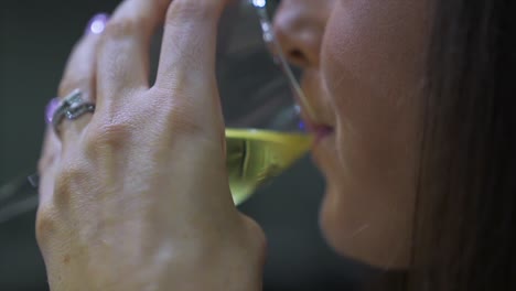 attractive caucasian woman drinking a glass of white wine and smiling in a restaurant in slow motion