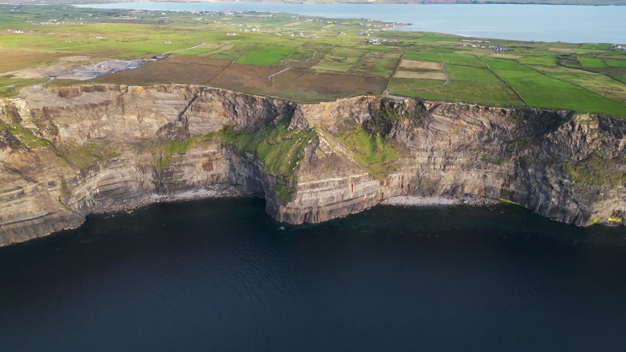 disparo de avión no tripulado volando hacia atrás lejos de los acantilados de moher al atardecer