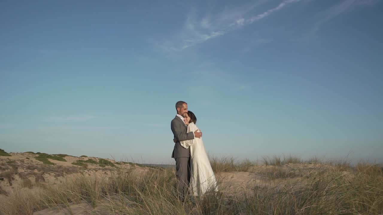 Nygift par omfavner hinanden ved havet