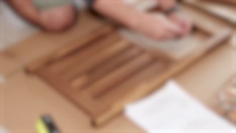 hands assembling wooden furniture using a screwdriver and instructions on a table with soft lighting