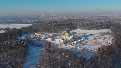 Aerial-view-of-the-Pazaislis-monastery-and-the-Church-of-the-Visitation-in-Kaunas,-Lithuania-in-winter,-snowy-landscape,-Italian-Baroque-architecture,-flying-around,-away-from-it,-side-of-monastery