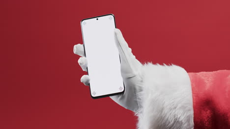 video of santa claus holding smartphone with copy space on red background