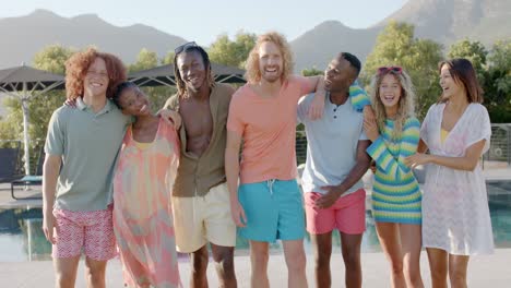 portrait of happy diverse friends standing with arms around at sunny pool party, slow motion