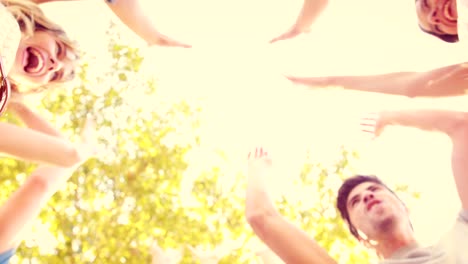 happy friends stacking hands together in the park