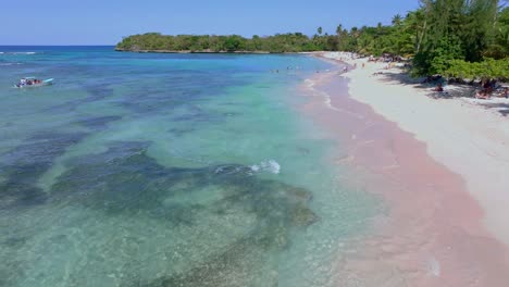 Sobrevuelo-De-Drones-Sobre-Una-Playa-De-Arena-Y-Agua-Clara-Con-Muchos-Turistas-En-El-Agua