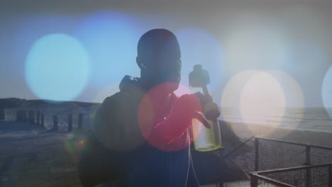 animation of spots over african american man drinking water outdoors