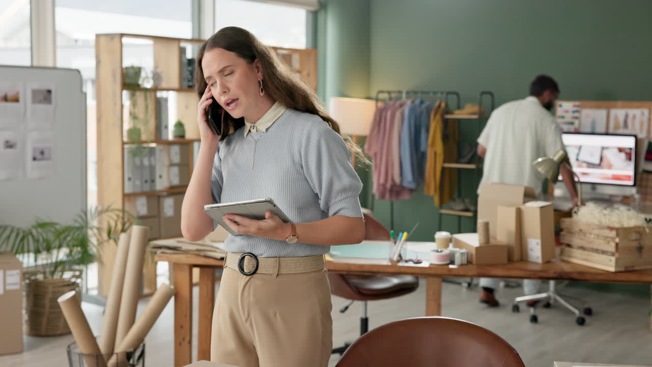 Woman on a phone call holding a tablet in a small business office