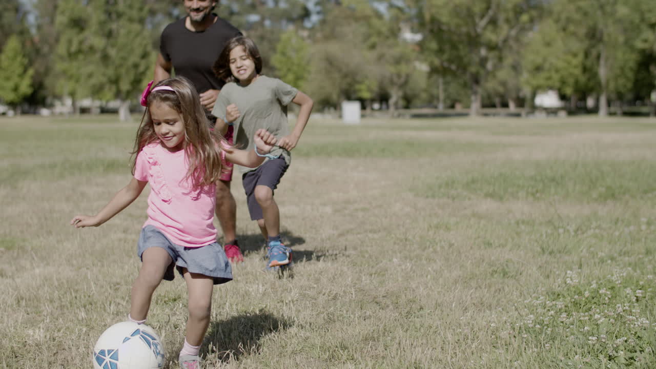 vista frontal de papá con discapacidad y niños pateando la pelota