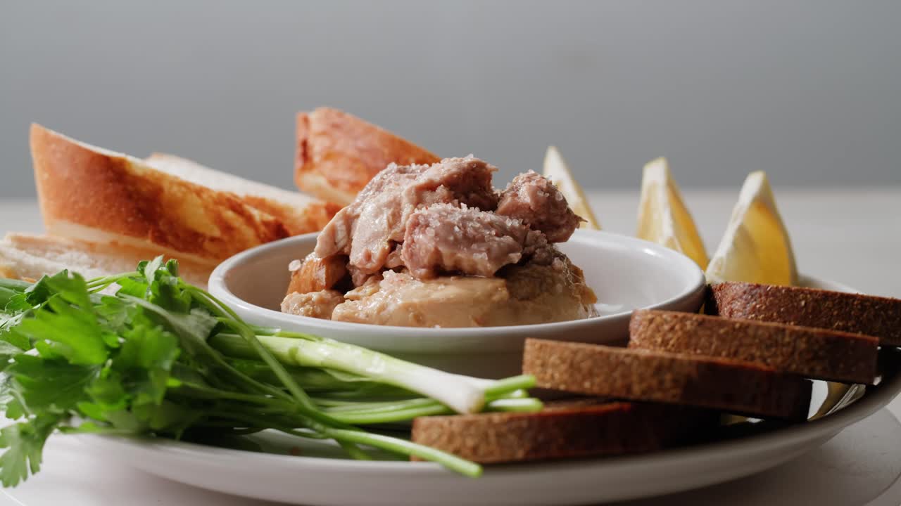 Smoked cod liver in oil in open tin can with fresh greens on wooden table. Seafoods delicacy. High quality 4k footage