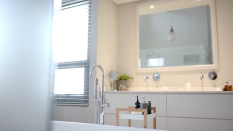 Close-up-of-sunny-white-bathroom-with-freestanding-bathtub,-slow-motion