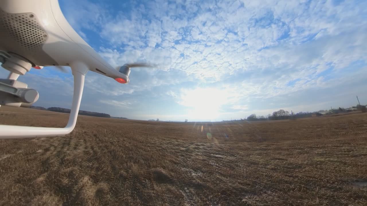 들판 위로 앞으로 날아가는 dji 팬텀 4 쿼드콥터 드론의 클로즈업 측면 보기