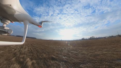 close-up side view of dji phantom 4 quadcopter drone flying forward over fields