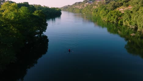 Kajakfahrer-Paddelt-Während-Des-Sonnenaufgangs-In-Austin,-Texas,-Durch-Spiegelglattes-Wasser,-Drohne-Zieht-Los,-Um-Die-Skyline-Der-Innenstadt-Vom-Redbud-Isle-Nature-Trail-Aus-Freizulegen