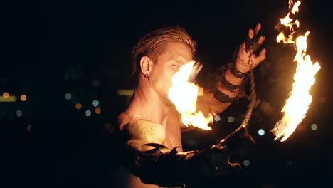 young blond male spins two burning pois around face slow motion shot close-up shot