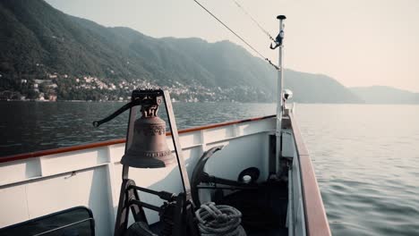 view of a boat's bow with bell and anchor sailing at lake como in lombardy, italy - pov shot