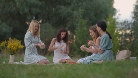 four young girls in the open air conduct a clay modeling class. joint activity communication laughter a common hobby a women's circle.