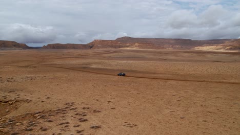 Areal-shot-of-a-drone-passing-a-vehicle-in-a-desert-in-Utah,-America