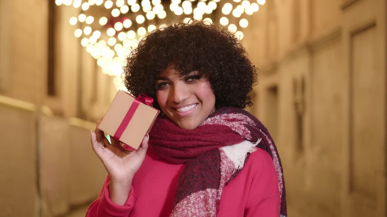 Woman with gift in winter with holiday lights