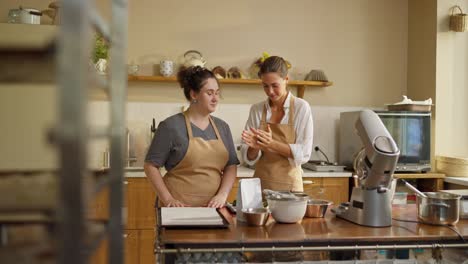 two women bake together in a bakery