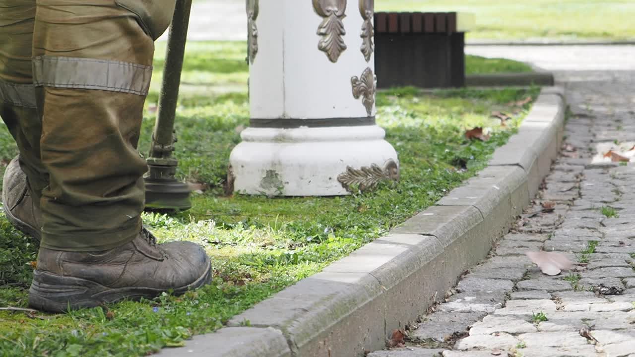 садовник в парке косит траву