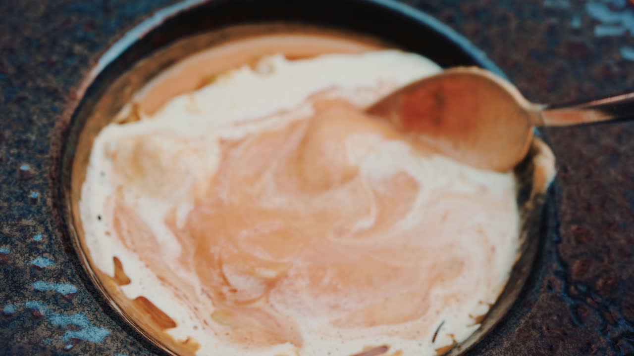 Close up of a spoon lifting creamy soup with smooth texture and warm colors