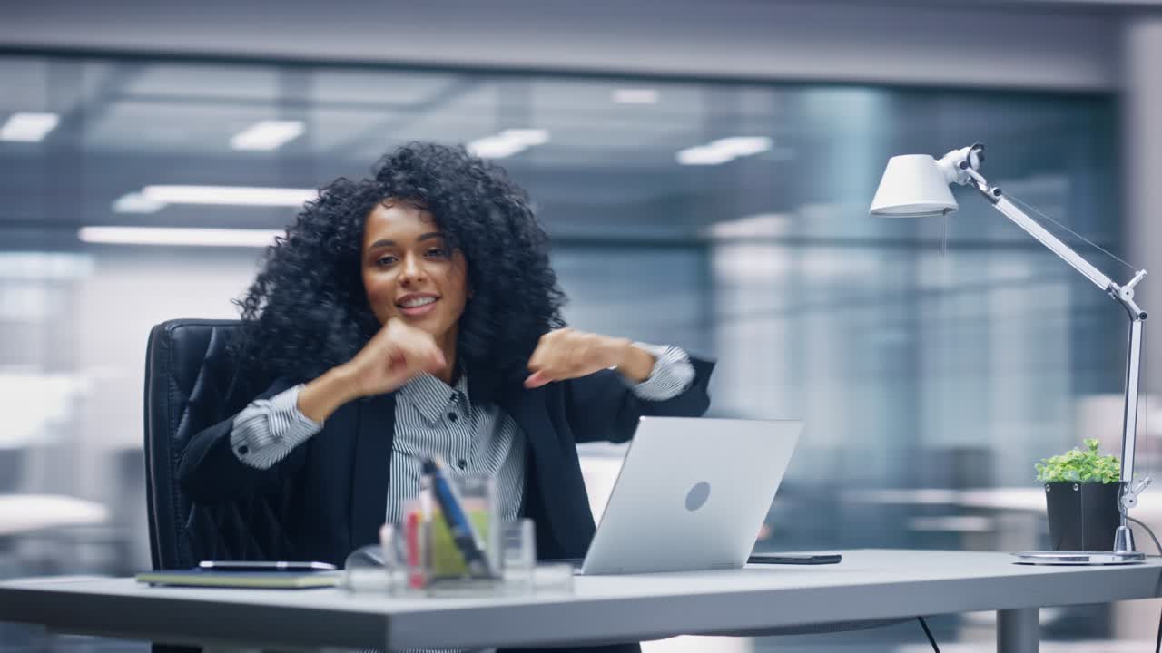 360 Degree Office: Black Businesswoman Dances and Smiles While Sitting at Her Desk. Beautiful Female Specialist Works on Laptop Celebrates Successful e-Commerce Project. Tracking Moving Around Shot