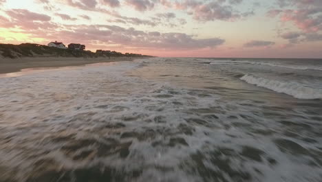 Eine-Filmische-Drohnenaufnahme,-Die-Tief-über-Dem-Ozean-Beginnt-Und-Dann-Aufsteigt,-Um-Strandhäuser-An-Der-Küste-Von-North-Carolina-Zu-Enthüllen