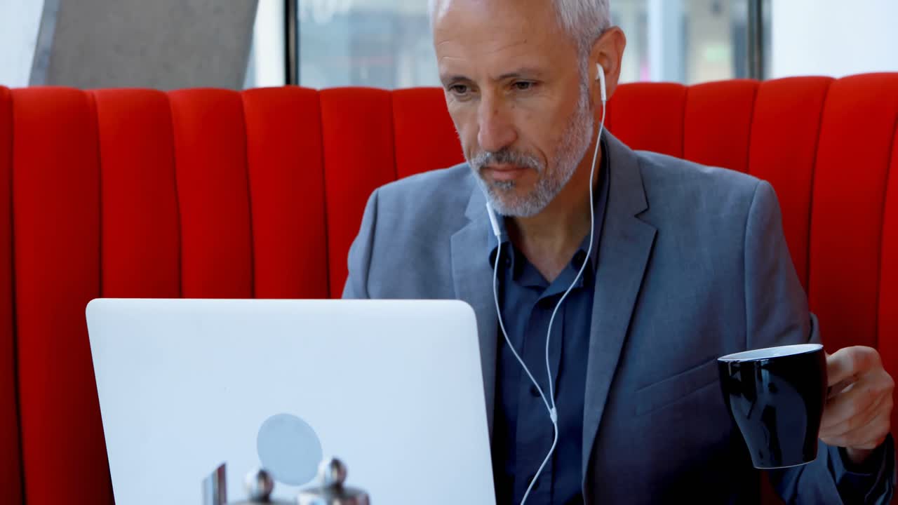 Uomo d'affari che prende un caffè mentre usa il laptop in hotel 4k