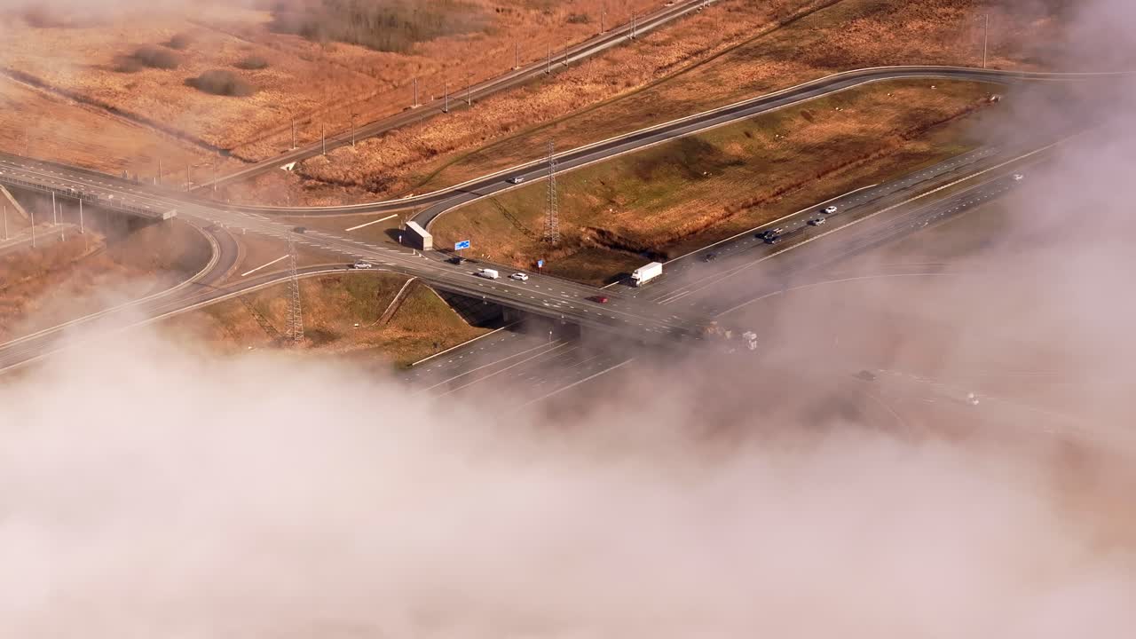 Aerial drone of road network disappearing into fog in early spring over Latvia