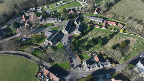 Rosedale-Abbey-Village,-Aerial-Footage,-North-York-moors-National-Park,-Slow-pull-back-from-over-village,-pan-upwards-to-landscape-vista-reveal