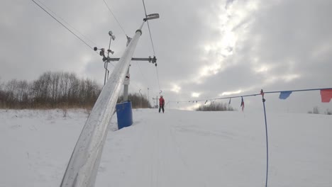 Skier-gliding-up-slope-on-t-bar-lift-in-winter-sports-resort