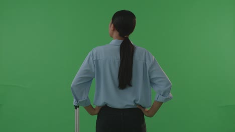 back view asian woman traveler with luggage standing with arms akimbo in the green screen background studio, during sunset time