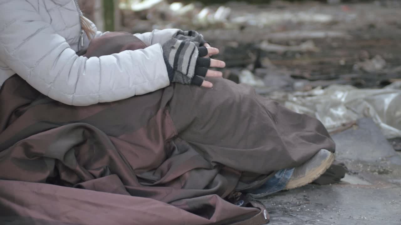 Homeless person wrapped in blanket in abandoned derelict building