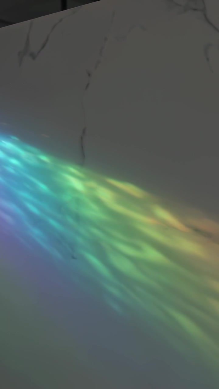 Vertical video: Appearing rainbow light moving across marble wall, revealing seam and reflection