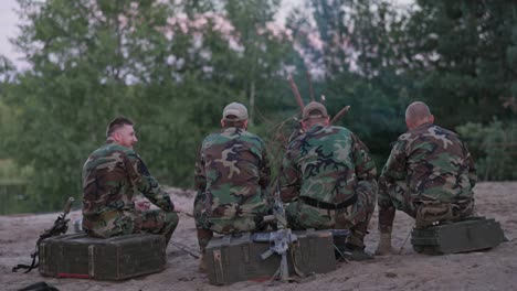 hunters in camouflage clothing after hunting game light a bonfire, fry sausages, tell each other a story, view from behind, hidden weapons, rest, smoke cigarettes