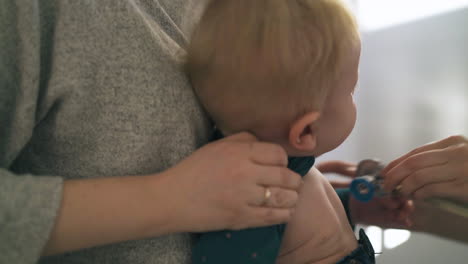 skilled therapist examines funny toddler in mother arms