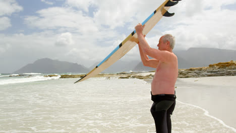 side view of old caucasian man carrying surfboard on his head at beach 4k