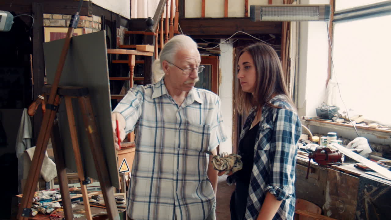 Artist teaching a student in a painting studio
