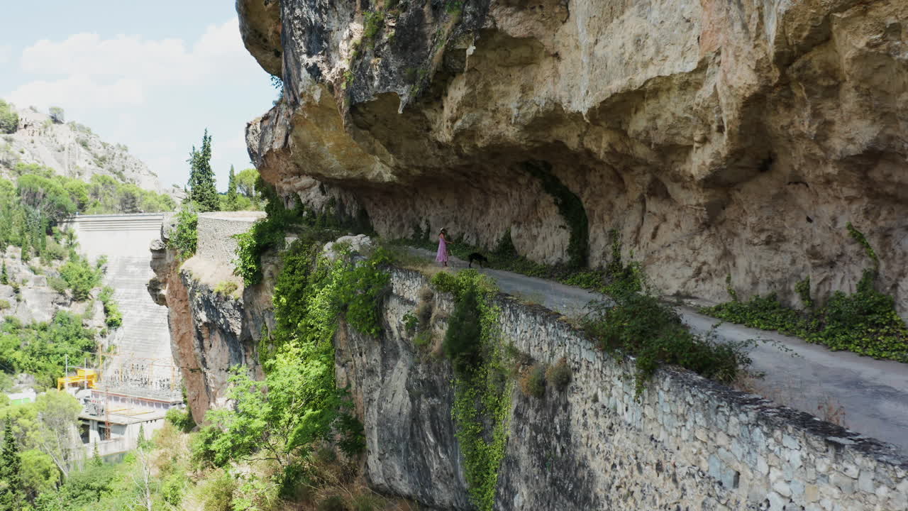 Woman walking her dog on a scenic cliffside road