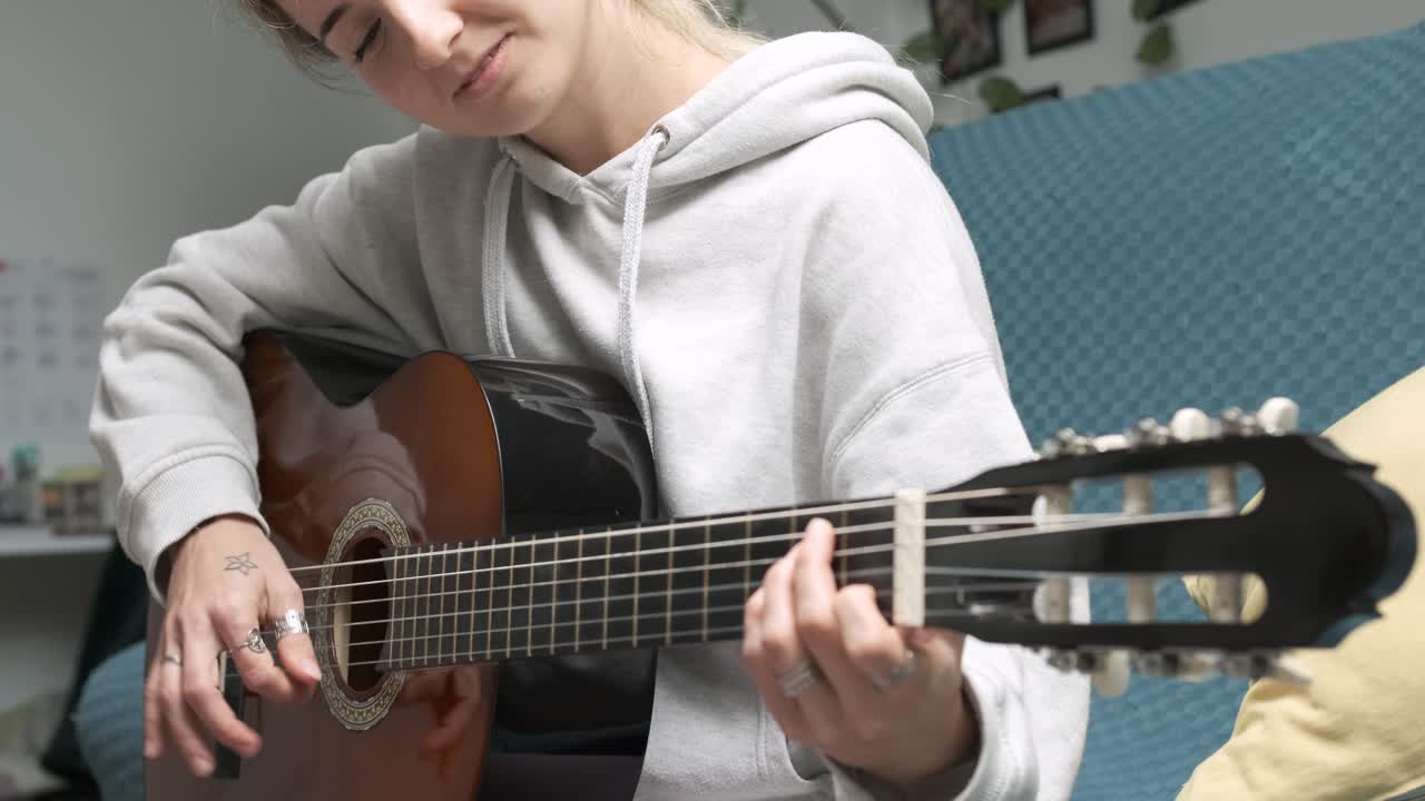 Young woman strumming an acoustic guitar in a cozy home environment